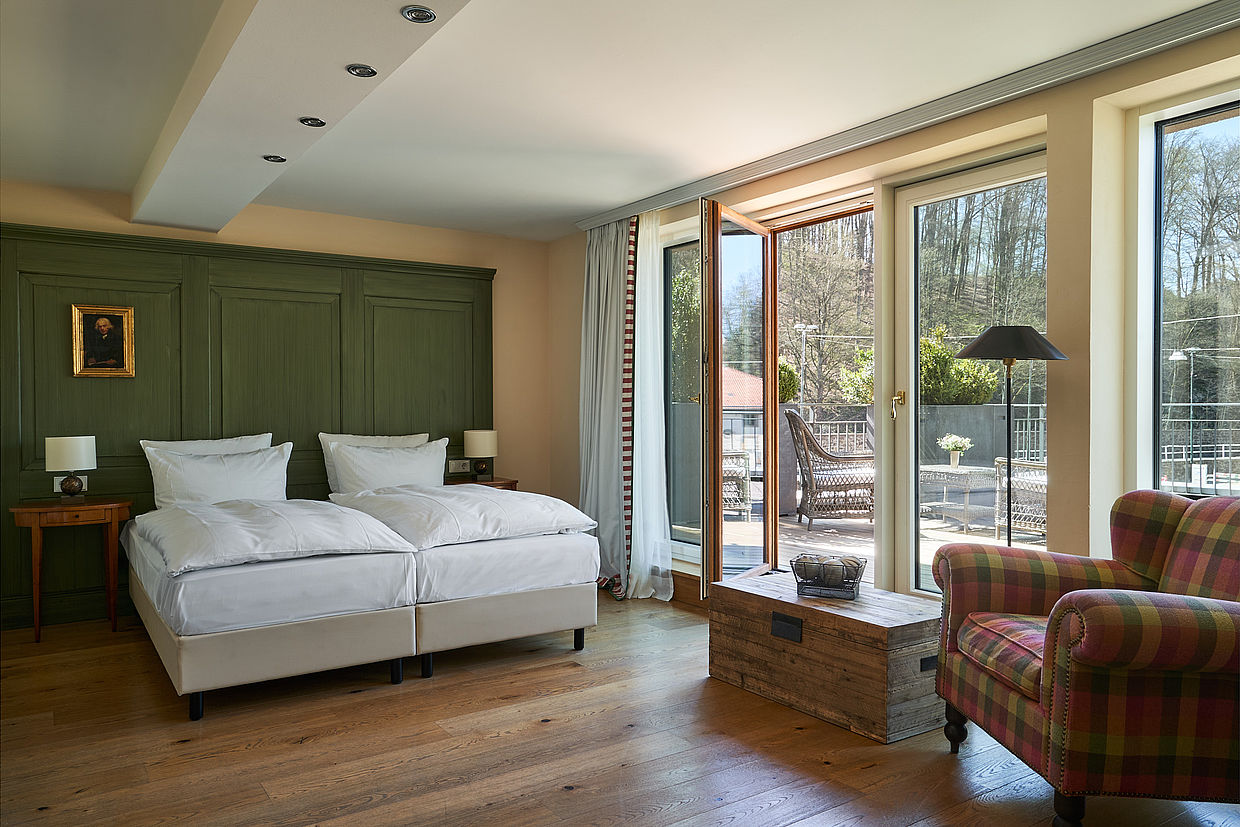 Ein Doppelbett und eine Sitzecke mit großen Fenstern in einem Zimmer im Hardenberg BurgHotel.
