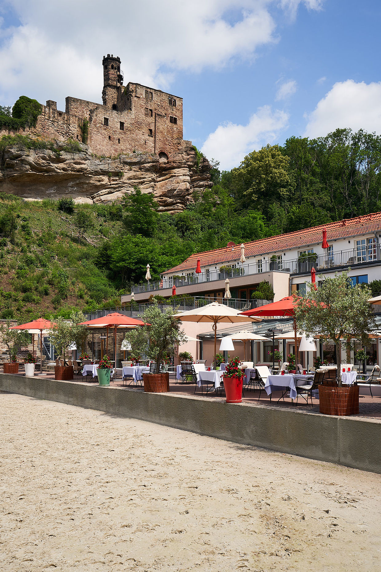 Außenansicht des Hotels unter der Burgruine und der dazugehörigen Restaurant Terrasse, ideal als Eventlocation in Niedersachsen.