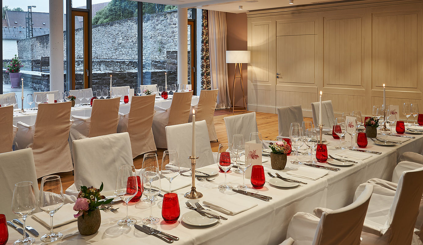Mit weißen Tüchern bedeckte Tische und Stühle, dekoriert für ein Event im Hardenberg BurgHotel