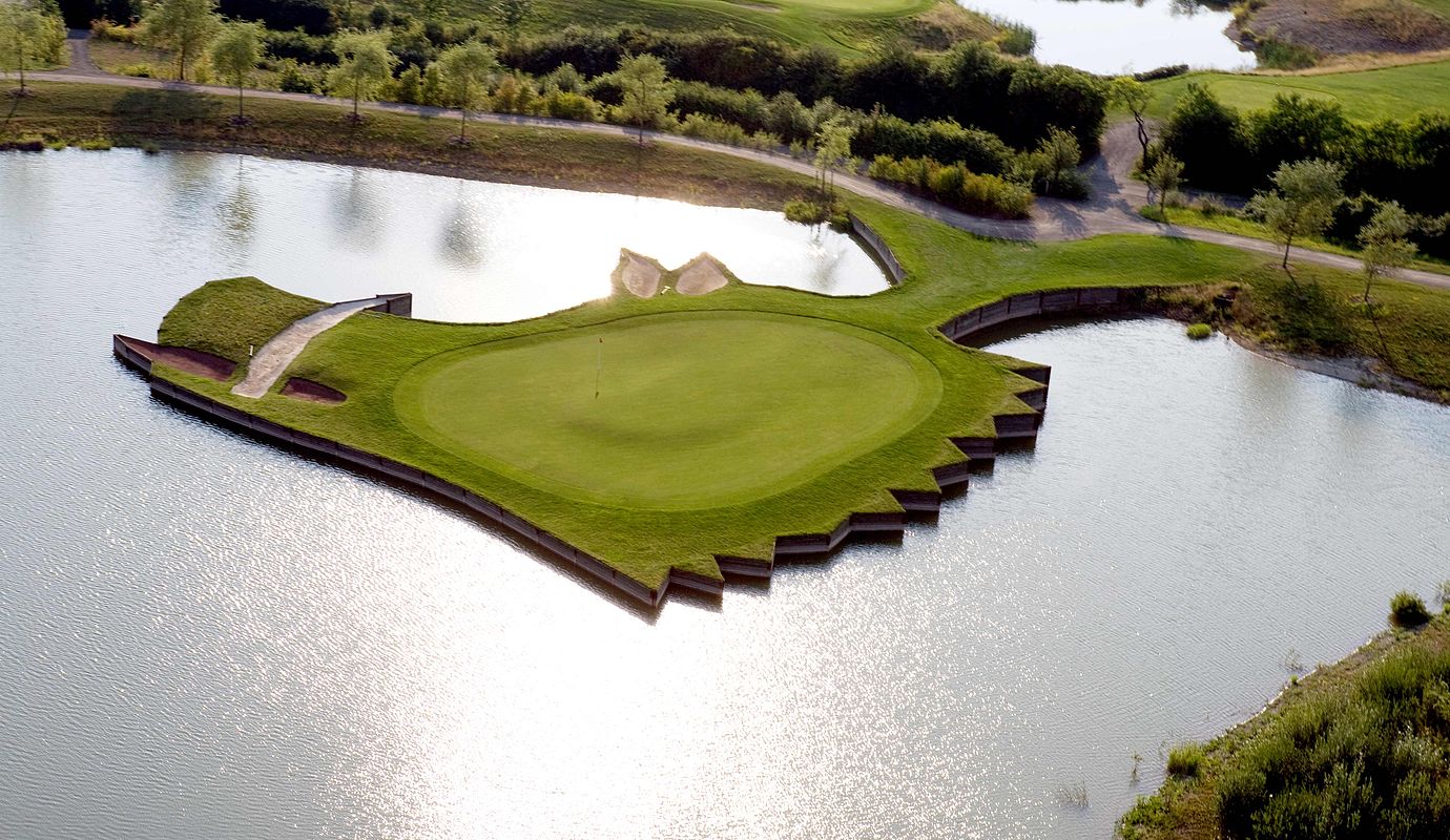 Luftaufnahme eines Golfplatzes mit einer ins Wasser ragenden Grünfläche beim Hardenberg BurgHotel.
