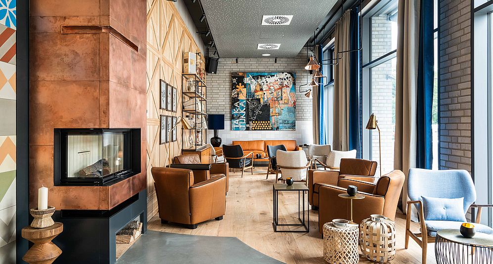 Die gemütliche und modern eingerichtete Lobby des Hotel FREIgeist Einbeck mit braunen Sesseln und großen Fenstern